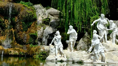 Statue bianche vicino a uno stagno con riflessi, circondate da alberi verdi