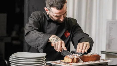 Chef che taglia una torta rettangolare con zucchero a velo