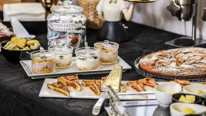 Buffet di dolci con crostata, budini e biscotti su tavolo nero