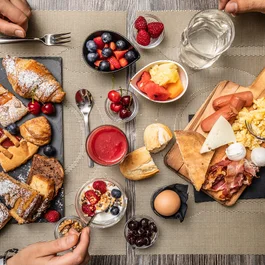 Colazione con dolci, frutta, uova, pancetta e pane su tavola