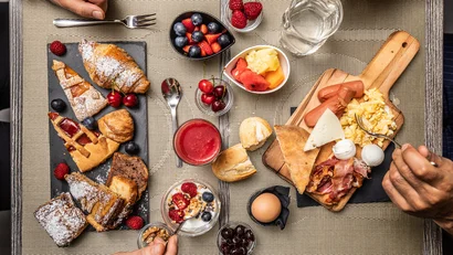 Colazione con dolci, frutta, uova, pancetta e pane su tavola