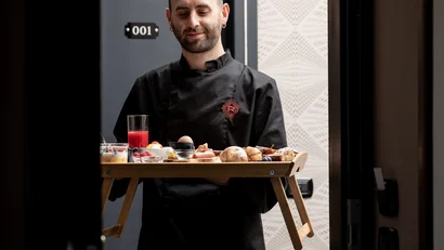 Cameriere che serve una colazione su un vassoio pieghevole davanti alla porta di una stanza