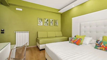 Camera da letto con pareti verdi, letto bianco e divano verde.